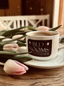 una taza de café y tulipanes rosas sobre una mesa en BedRooms Piotrkowska 64, en Łódź