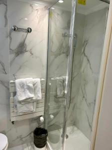 een douchecabine in een badkamer met wit marmer bij Hôtel Derby Eiffel in Parijs