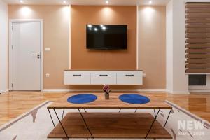 a living room with a table and a tv on a wall at Apartment Bisera in Ohrid