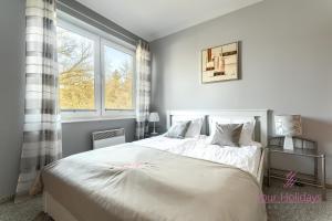 a bedroom with a large white bed with a window at Your Holidays Gryfa Pomorskiego in Międzyzdroje
