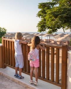 Deux petites filles debout sur une clôture en bois dans l'établissement Grand Waterworld Makadi Family Star - Couples and Families Only, à Hurghada