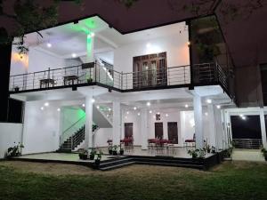 a white house with a balcony and tables and chairs at Jungle Lodge in Udawalawe