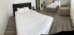 een slaapkamer met een groot wit bed en een stoel bij Hotel Restaurant Rolland in Montagnieu