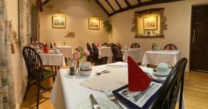 un restaurante con mesas blancas y sillas con servilletas rojas en Cotswold House, en Oxford