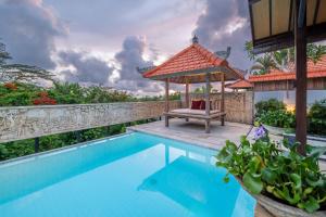 een zwembad met een prieel naast een huis bij Tropical Villa Asmara - 400sqm Garden Oasis with large Pool and Scenic Views in Uluwatu