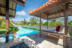 an outdoor patio with a bed and a swimming pool at Tropical Villa Asmara in Uluwatu