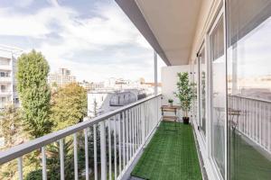 een balkon met groene vloeren en grote ramen bij Appartement avec parking et terrasse Métro 7 et Paris in Villejuif
