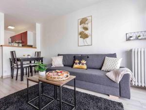 een woonkamer met een blauwe bank en een tafel bij Appartement avec parking et terrasse Métro 7 et Paris in Villejuif