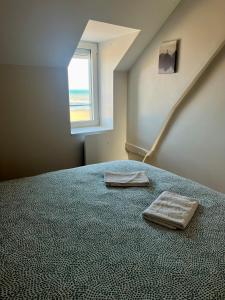 a bedroom with a bed with two towels on it at La Tourelle - Balcon vue mer et terrasse plein sud in Saint-Aubin-sur-Mer