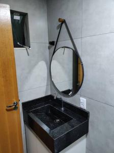 Apartamento encantador 1 Quarto na Candangolândia في برازيليا: حمام مع حوض أسود ومرآة
