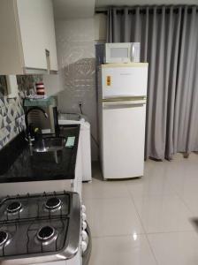 una pequeña cocina con fogones y nevera. en Apartamento encantador 1 Quarto na Candangolândia en Brasilia