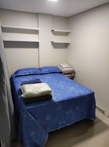 1 dormitorio con cama azul y almohada en Apartamento encantador 1 Quarto na Candangolândia en Brasilia