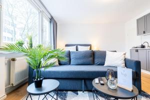 a blue couch in a living room with a potted plant at lionApartments Leverkusen in Leverkusen