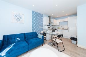 ein Wohnzimmer mit einem blauen Sofa und einer Küche in der Unterkunft Free Parking 2Bed Flat Weekly/Monthly Stay Saving in Reading