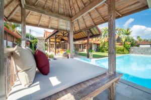 an outdoor bed in a villa with a swimming pool at Tropical Villa Asmara in Uluwatu