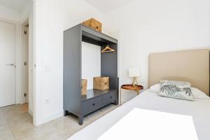 a white bedroom with a bed and a cabinet at AB Beach Poble Nou in Barcelona