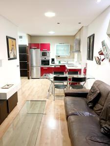 sala de estar con sofá y cocina con armarios rojos. en OceanFront Flat III by Canary365, en Las Palmas de Gran Canaria