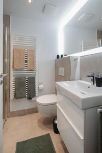 La salle de bains blanche est pourvue de toilettes et d'un lavabo. dans l'établissement die ELF, à Norderney