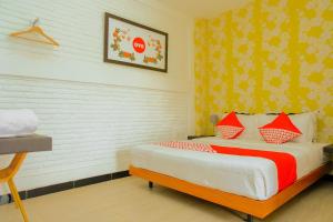 a bedroom with a bed with red and orange pillows at OYO 354' 32 Guest House in Batu