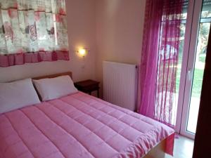 a pink bed in a room with a window at Panormos Serene Nests - Gateways to Achaia in Psathopirgos