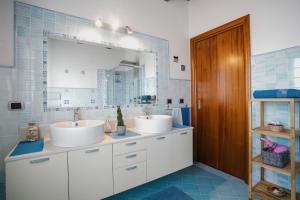 łazienka z 2 umywalkami i dużym lustrem w obiekcie B&B Le Ginestre w mieście Portoscuso