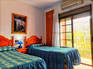1 dormitorio con 2 camas y ventana con balcón en Hostal Restaurante Solaire, en Castañar de Ibor