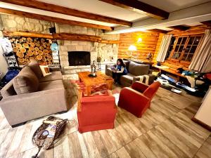 uma mulher sentada numa sala de estar com lareira em Las Marianas Hotel em San Carlos de Bariloche