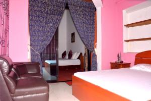 ein Schlafzimmer mit einem Bett, einem Stuhl und einem Spiegel in der Unterkunft The Kings Villa in Wattala