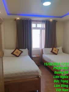 2 camas en una habitación con ventana e ainyl en Khách sạn Hoàng Hảo, en Ðưc Trọng