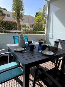 uma mesa preta com pratos e um vaso na varanda em 21 - Très agréable rdc avec terrasse et parking em Bandol