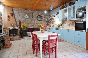 uma cozinha com uma mesa branca e cadeiras vermelhas em Kalavrita Winter Retreat - Homely Spacious Chalet em Áno Vlasía