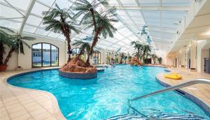 a large swimming pool with palm trees in a building at Lovely Chalet - Welcome Holiday Park Dawlish warren in Bellaghy