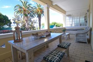 a porch with a table and a view of the ocean at On The Square Luxury Apartment in Simonʼs Town