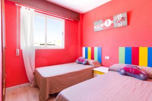 Habitación roja con 2 camas y ventana en Atico vistas Playa Gandia, en Gandía