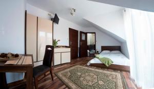 a bedroom with a bed and a desk and a table at Willa JANTAR in Dębki