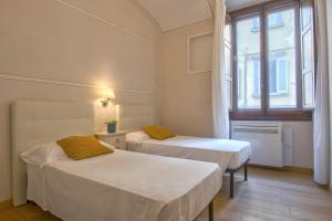 two beds in a room with a window at Casa Michelangelo & Giotto - Tintori apt in Florence