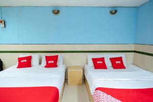 two beds in a room with red and white pillows at OYO 90208 Milion Inn in Miri
