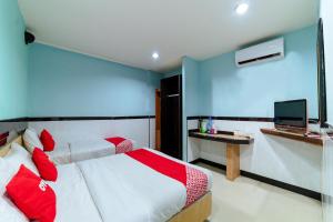 a bedroom with two beds and a desk with a television at OYO 90208 Milion Inn in Miri