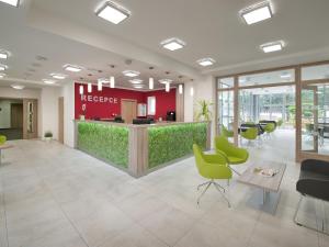 an office lobby with a reception desk and green chairs at EA Rodinné chatky Kraskov in Kraskov