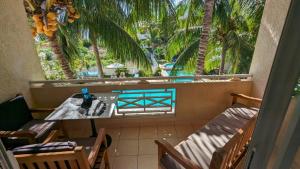 Un balcón con mesa y sillas y palmeras. en Charming Beach Apartment - Charmant Appart de Plage, en Flic en Flac