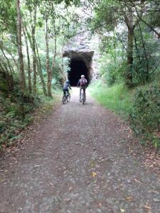 two people riding bikes in front of a tunnel at Sons do Eo- Apartamentos rurales sostenibles en Baleira Lugo in Baleira