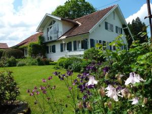 a white house with flowers in the yard at Apartment in Thuringia in Rettenberg