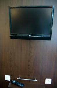 a flat screen tv on a wooden wall with two remote controls at Le Mokca in Meylan