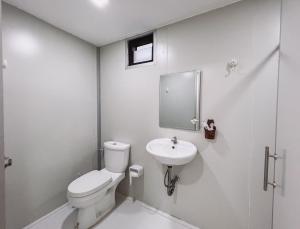 a white bathroom with a toilet and a sink at Pang Long Chao resort in Trang