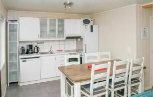 una cocina con armarios blancos y una mesa y sillas de madera. en Stunning Home In Sjernary With Kitchen, en Sjernarøy