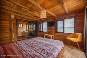 a bedroom with a bed and a chair and windows at LE VILLAGE D'HÉLÈNE - Natura Resort in Ouidah +28 photos