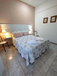 une chambre avec un grand lit blanc avec des oreillers roses dans l'établissement AMALIA departamentos, à San Rafael