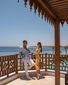 Ein Mann und eine Frau stehen auf einer Veranda in der Nähe des Ozeans. in der Unterkunft The Makadi Spa Hotel - Couples Only 18 Years Plus in Hurghada