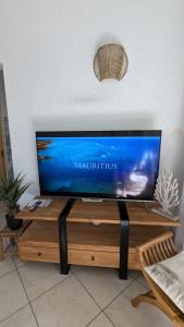TV de pantalla plana sobre una mesa de madera en Charming Beach Apartment - Charmant Appart de Plage, en Flic en Flac