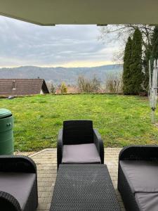 un patio con 2 sillas, un sofá y un campo en Kleine Ferienwohnung - Nähe Schweizergrenze, en Hohentengen